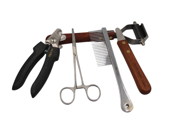 A pair of claw nippers, a plucking clamp, a comb, and a trimming knife are leaning against an underwool rake. Link: Category Grooming tools.